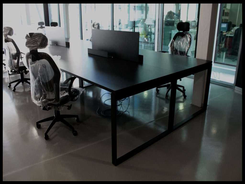 Mesa de trabajo de tablero oscuro con estructura metálica rectangular.