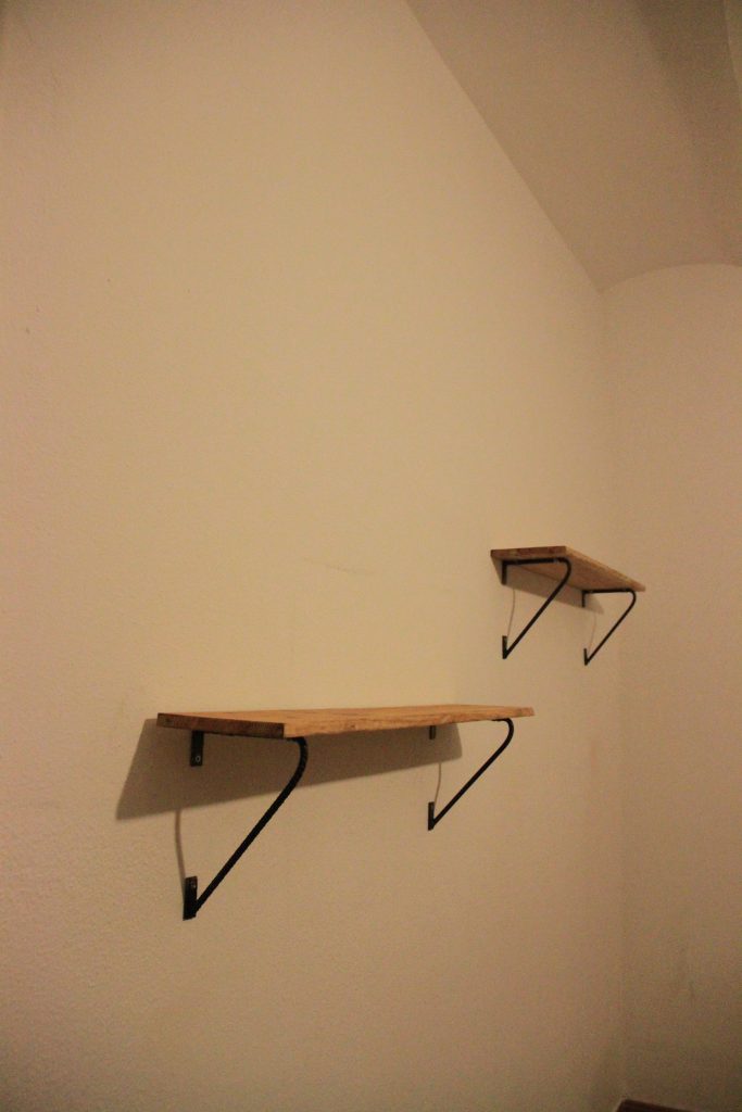 Estante de pared de madera con soportes metálicos curvos.