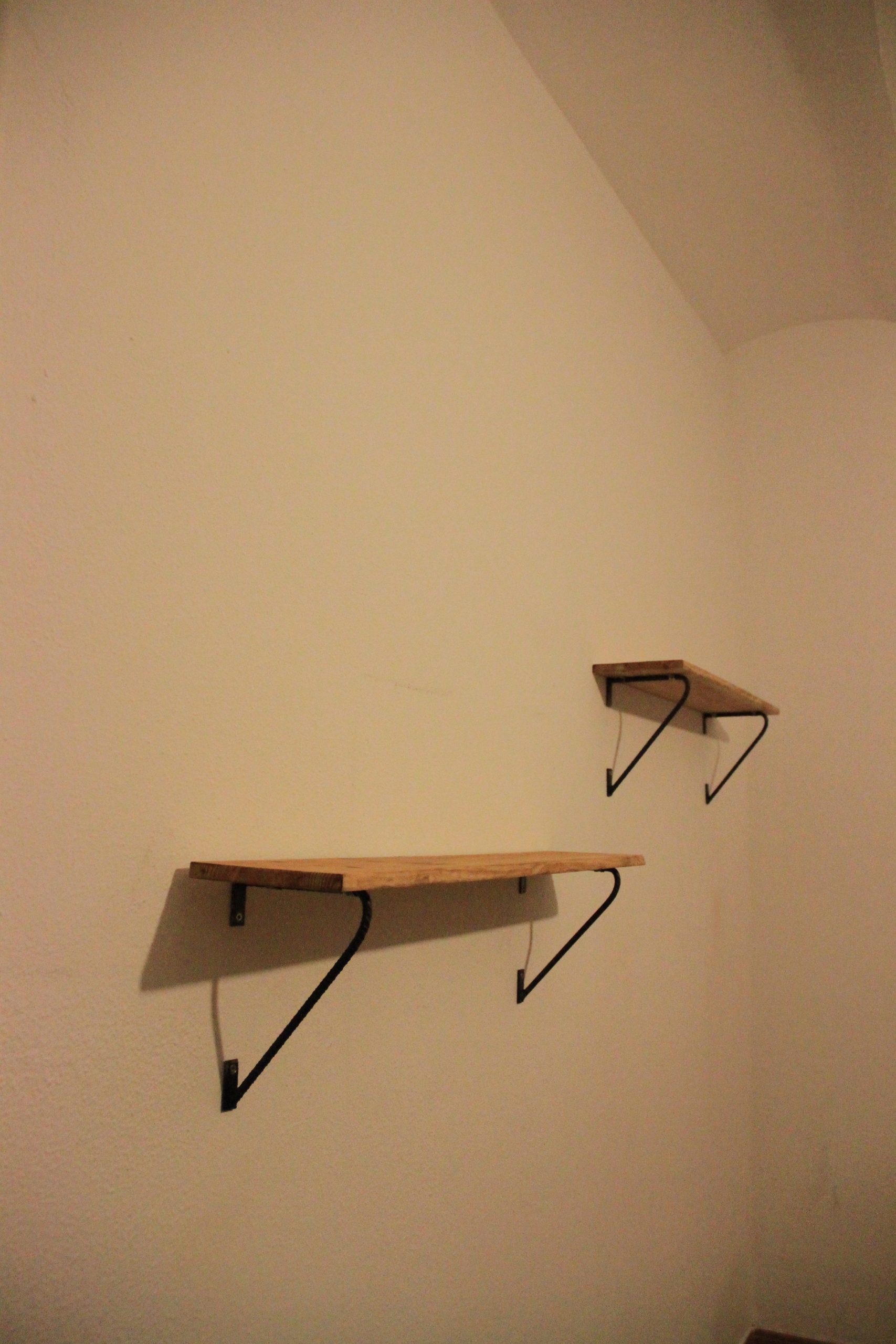 Estante de pared de madera con soportes metálicos curvos.