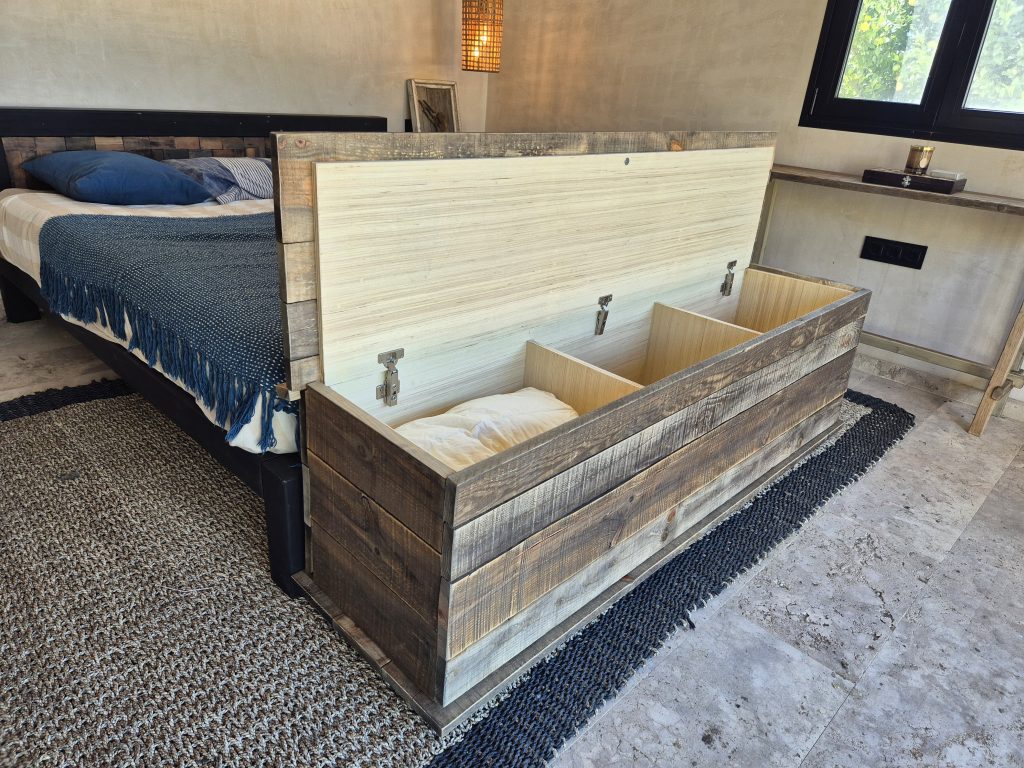 Arcón de madera abierto, con compartimentos interiores y base metálica.