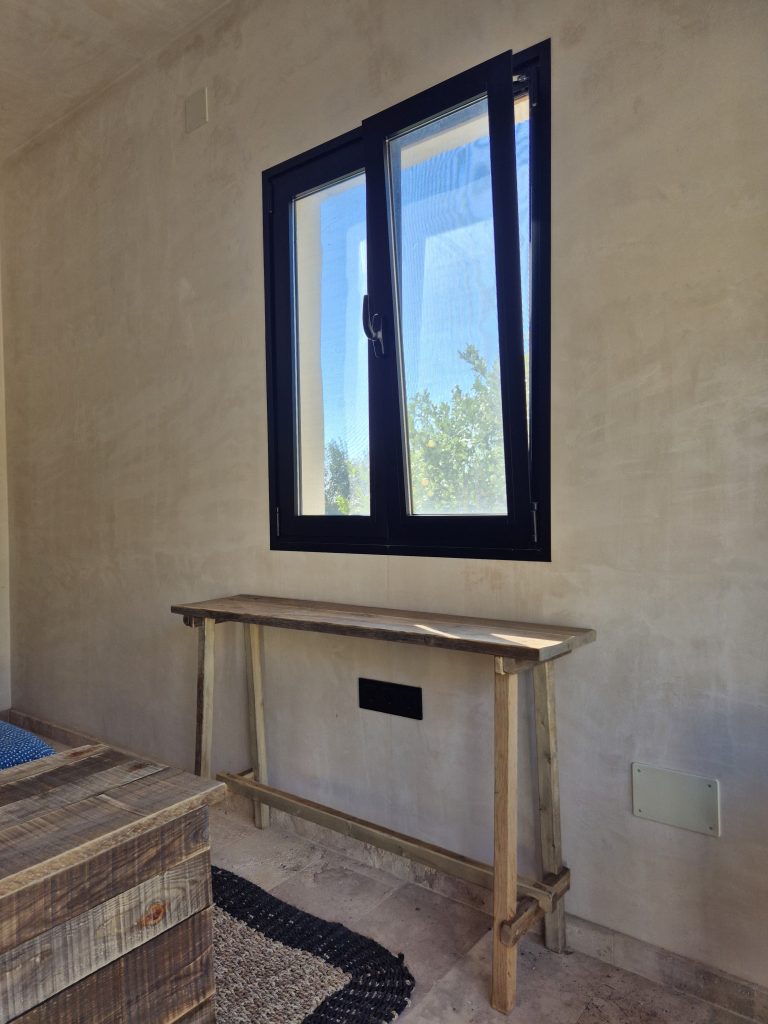 Consola de madera junto a una pared bajo una ventana.