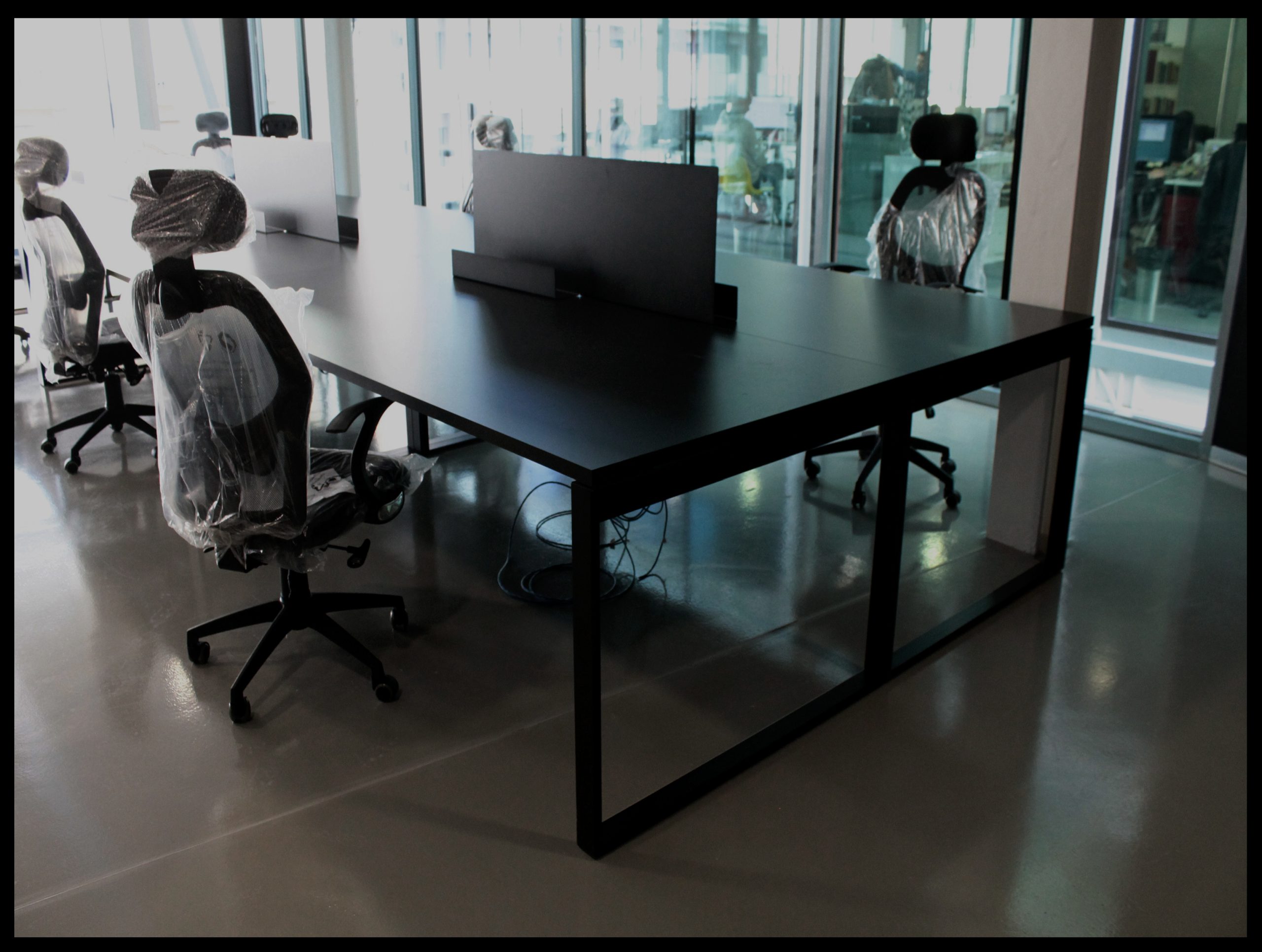 Mesa de trabajo de tablero oscuro con estructura metálica rectangular.